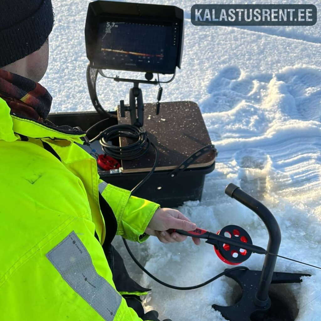 Jääpüük live-kajaloodiga – kala jälgimine reaalajas Kalastaja jääpüügil kasutamas live-kajaloodi: ekraan kalastuskastil, andur jääaugus ja ritv käes, taustal lumine järvejää ning Kalastusrent.ee logo.